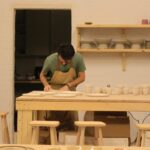 A potter working meticulously in a cozy workshop, creating unique ceramic pieces.