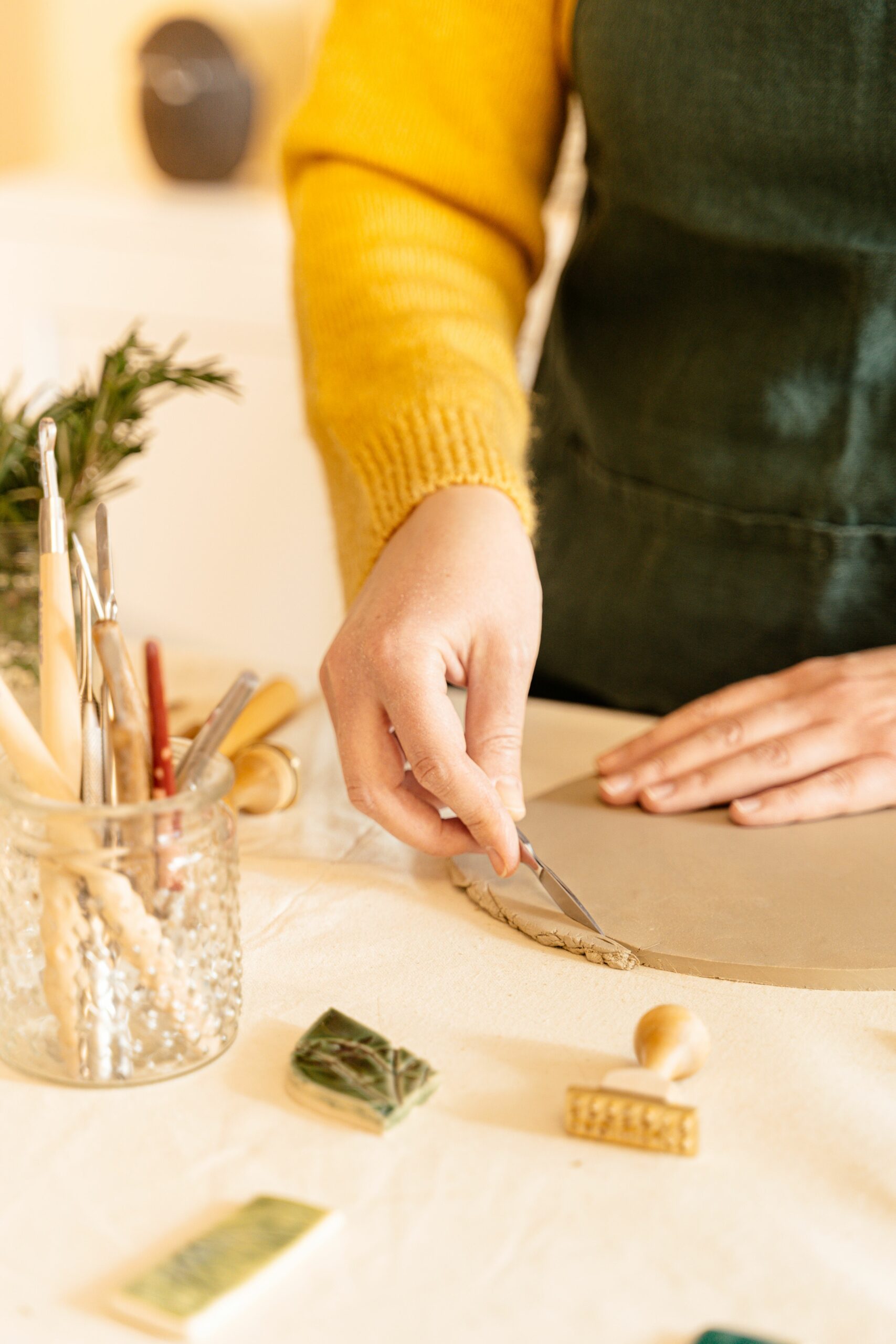 Close-up of a woman shaping clay with tools in an artisan studio, highlighting creativity and skill.