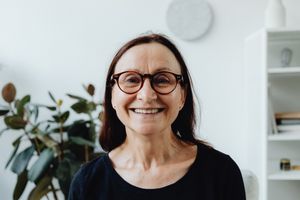 Portrait of a happy elderly woman wearing glasses, smiling in an indoor setting.