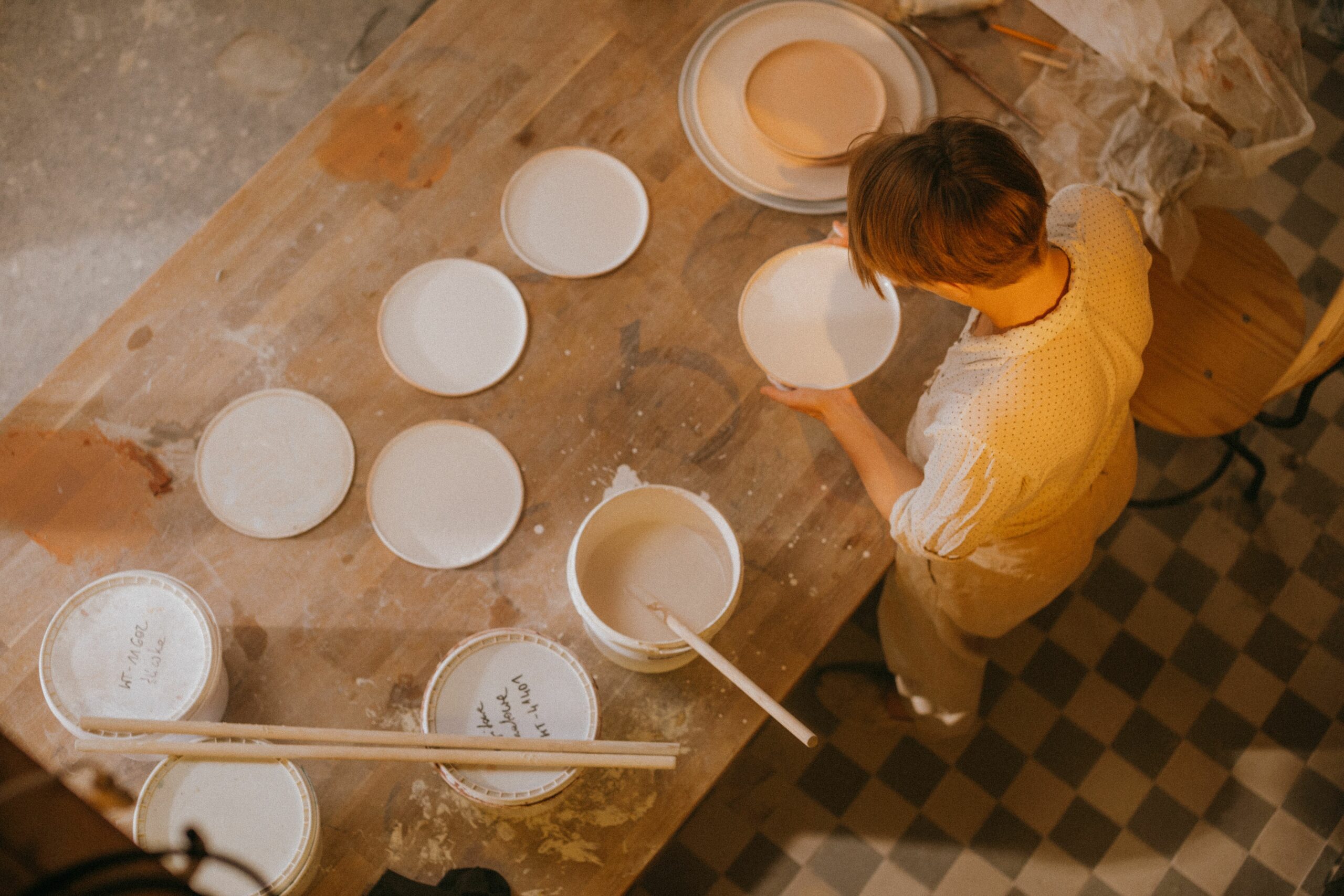 Aerial view of an artisan crafting ceramic plates in a workshop. Highlighting the handmade process.